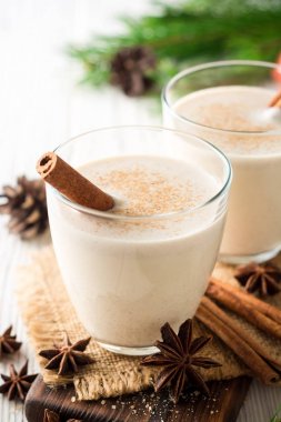 Rendelenmiş küçük hindistan cevizi ve tarçın Beyaz ahşap masa üzerinde ev yapımı yumurta likörü. Geleneksel Noel içki.