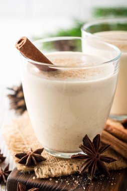 Rendelenmiş küçük hindistan cevizi ve tarçın Beyaz ahşap masa üzerinde ev yapımı yumurta likörü. Geleneksel Noel içki.