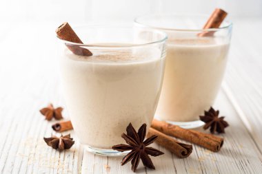 Rendelenmiş küçük hindistan cevizi ve tarçın Beyaz ahşap masa üzerinde ev yapımı yumurta likörü. Geleneksel Noel içki.