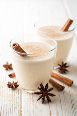 Rendelenmiş küçük hindistan cevizi ve tarçın Beyaz ahşap masa üzerinde ev yapımı yumurta likörü. Geleneksel Noel içki.