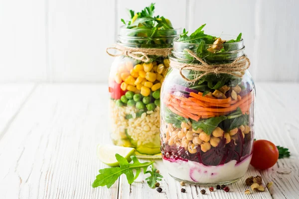 Ensaladas caseras saludables con garbanzos, bulgur y verduras en tarros de albañil sobre fondo de madera blanca . — Foto de Stock