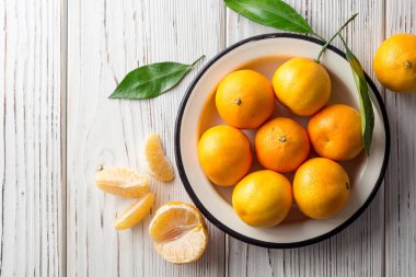 Beyaz ahşap zemin üzerinde plaka taze mandalina.