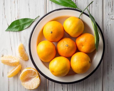 Beyaz ahşap zemin üzerinde plaka taze mandalina.