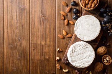 Camembert ve brie peyniri üzüm ve fındık ile ahşap kesme tahtası üzerinde.