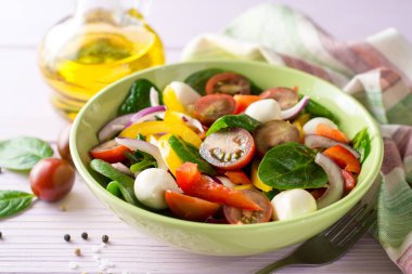 Ispanak, biber, domates, kırmızı soğan ve mozzarellalı mor ahşap zemin üzerine taze salata.