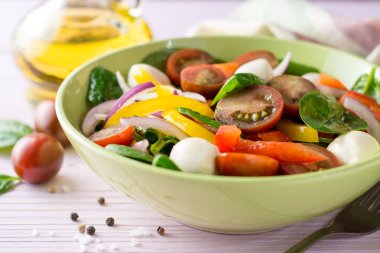 Ispanak, biber, domates, kırmızı soğan ve mozzarellalı mor ahşap zemin üzerine taze salata.