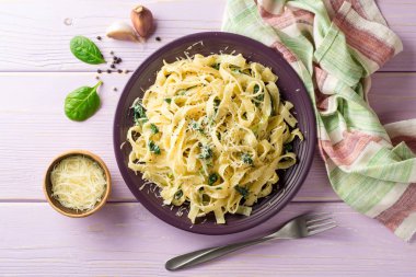 Tagliatelle makarna ıspanak, sarımsak ve Parmesan peyniri mor ahşap zemin üzerine.