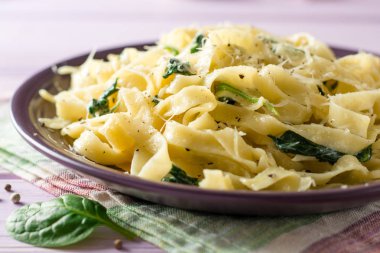 Tagliatelle makarna ıspanak, sarımsak ve Parmesan peyniri mor ahşap zemin üzerine.