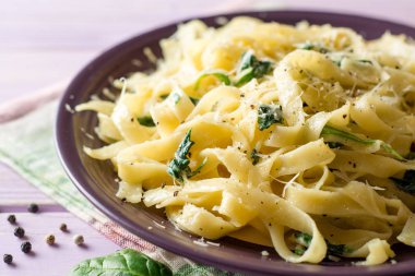 Tagliatelle makarna ıspanak, sarımsak ve Parmesan peyniri mor ahşap zemin üzerine.