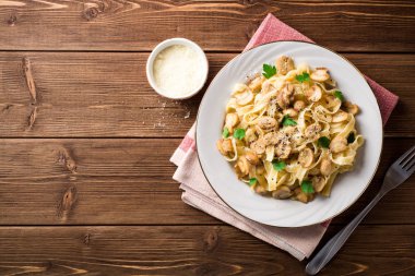 Tagliatelle makarna mantar, maydanoz ve ahşap masa üzerinde Parmesan peyniri ile.