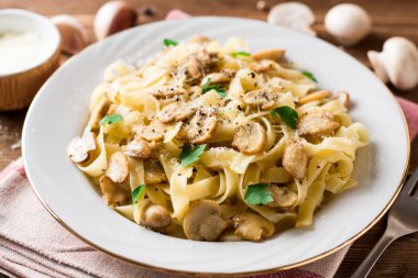 Tagliatelle makarna mantar, maydanoz ve ahşap masa üzerinde Parmesan peyniri ile.