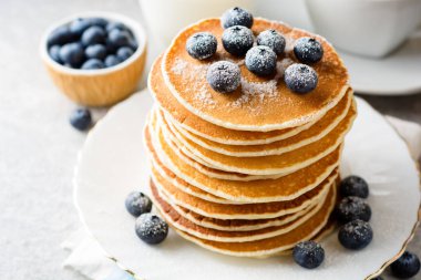 Yaban mersini ve gri taş zemin üzerine şeker ile Pancakes.