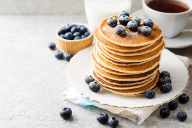 Yaban mersini ve gri taş zemin üzerine şeker ile Pancakes.