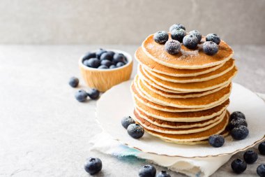 Yaban mersini ve gri taş zemin üzerine şeker ile Pancakes.