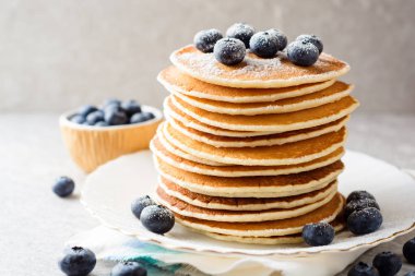 Yaban mersini ve gri taş zemin üzerine şeker ile Pancakes.