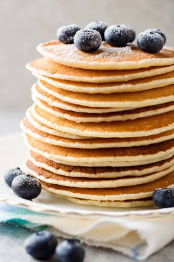 Yaban mersini ve gri taş zemin üzerine şeker ile Pancakes.