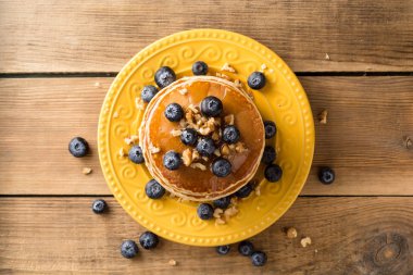 Yaban mersini, ceviz ve ahşap zemin üzerine ballı krep.