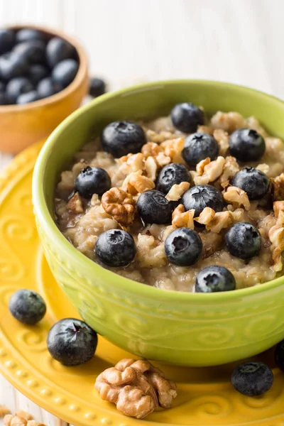 Yaban mersini, ceviz ve Beyaz ahşap zemin üzerinde ballı yulaf lapası.