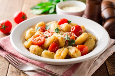 Ev yapımı İtalyan gnocchi ahşap masa üzerinde domates, sarımsak, maydanoz ve parmesan peyniri ile.