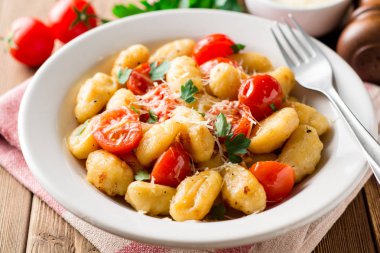 Ev yapımı İtalyan gnocchi ahşap masa üzerinde domates, sarımsak, maydanoz ve parmesan peyniri ile.