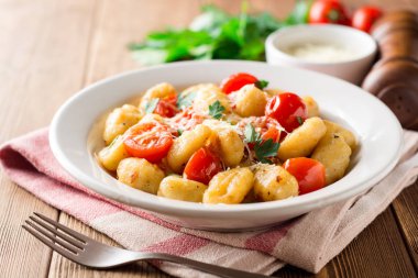 Ev yapımı İtalyan gnocchi ahşap masa üzerinde domates, sarımsak, maydanoz ve parmesan peyniri ile.