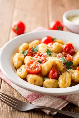 Ev yapımı İtalyan gnocchi ahşap masa üzerinde domates, sarımsak, maydanoz ve parmesan peyniri ile.