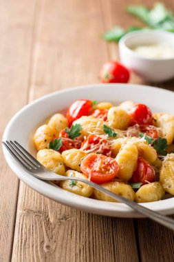Ev yapımı İtalyan gnocchi ahşap masa üzerinde domates, sarımsak, maydanoz ve parmesan peyniri ile.