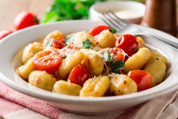 Gnocchi italiano casero con tomate, ajo, perejil y queso parmesano sobre mesa de madera . — Foto de Stock