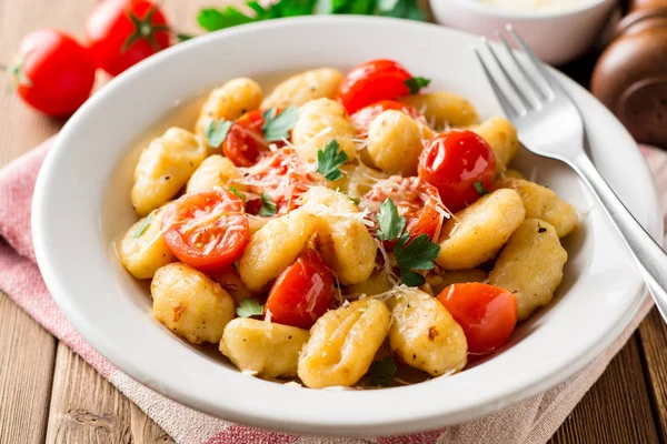 Ev yapımı İtalyan gnocchi ahşap masa üzerinde domates, sarımsak, maydanoz ve parmesan peyniri ile. — Stok fotoğraf