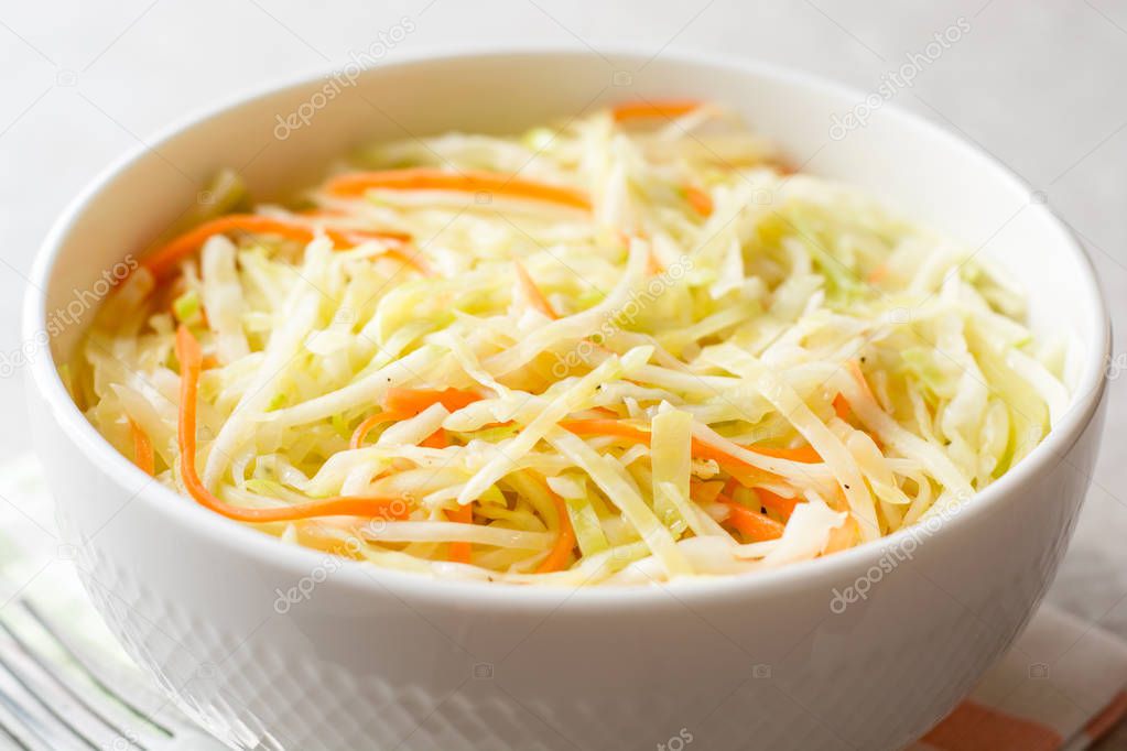 Fresh coleslaw salad in bowl on gray stone background.