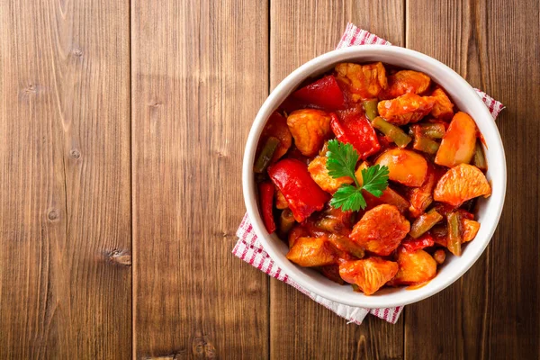 Estofado de pavo con pimientos, judías verdes y tomates en tazón sobre mesa de madera oscura — Foto de Stock