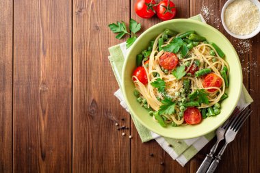 Spagetti Makarna ile yeşil fasulye, bezelye, domates, maydanoz ve parmesan peyniri ahşap tablo