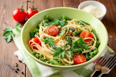 Spagetti Makarna ile yeşil fasulye, bezelye, domates, maydanoz ve parmesan peyniri ahşap tablo