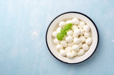 Mini mozzarella peyniri mavi beton arka planda demir tabakta.