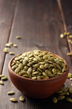 Koyu ahşap arka planda seramik kasede kabak çekirdeği. Seçici odak.