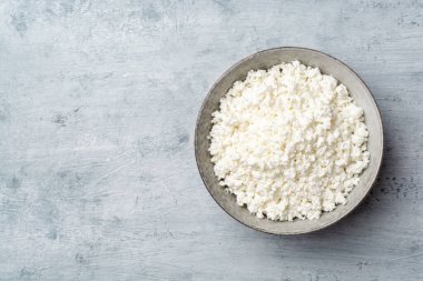 Beton arka planda kabın içindeki süzme peynir. Üst görünüm, alanı kopyala.