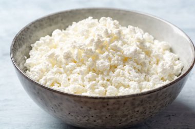 Beton arka planda kabın içindeki süzme peynir. Seçici odak.