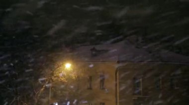 Kar yağışı gece bir sokak lambası ışığında şehirde