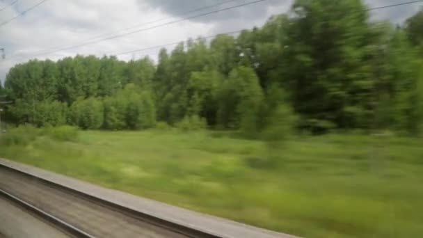 Widok z okna pociągu samochodu. Szyny, krajobraz, drzewa, lato słoneczny dzień — Wideo stockowe
