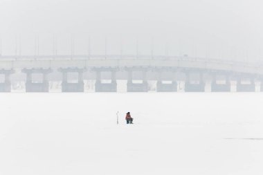 Buzda kış balıkçılığı. Rusya, Saratov 'daki Volga nehri. Ufuktaki yol köprüsü
