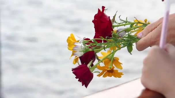手の中の水の背景に赤と黄色の花の花束 大祖国戦争のスターリングラードの戦い倒れたのメモリで ヴォルガ川のヴォルゴグラードの船に乗る — ストック動画