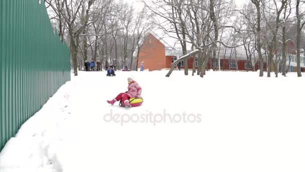 Дети и взрослые зимой катаются на надувных санях и трубах — стоковое видео