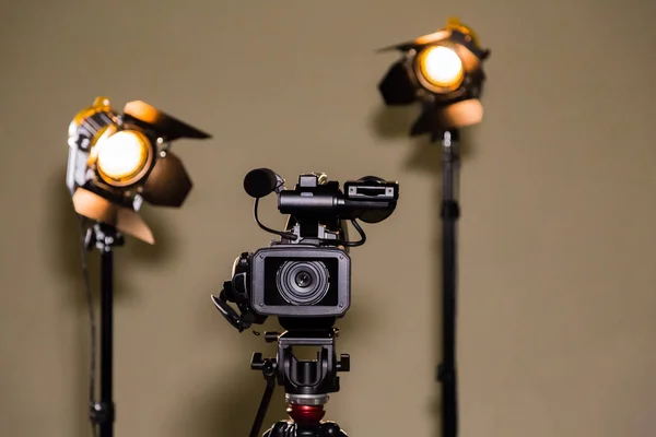 Videocámara (videocámara) en un trípode y dos proyectores halógenos con lentes Fresnel. Disparar una entrevista . —  Fotos de Stock