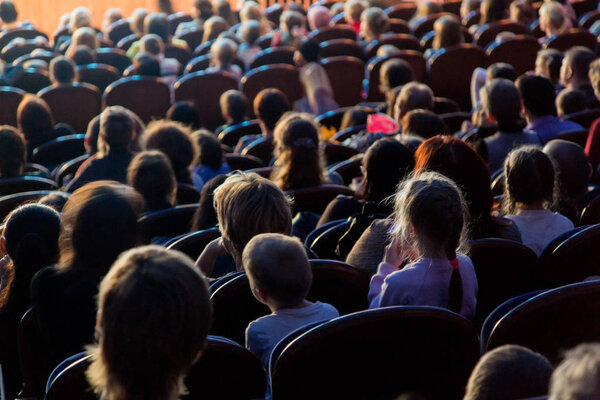 People, children, adults, parents in the theater watching the performance.