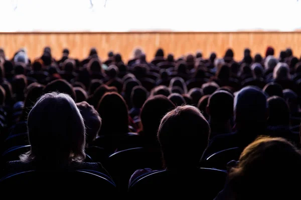 Pessoas no auditório a olhar para o palco. Tiroteio pelas costas — Fotografia de Stock