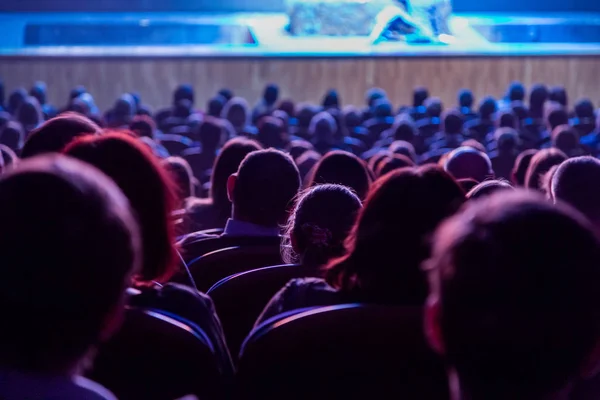 Pessoas no auditório a olhar para o palco. Tiroteio pelas costas — Fotografia de Stock