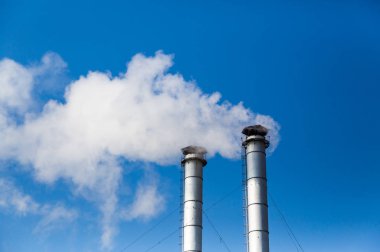 Mavi gökyüzü arka planda bir ısıtma tesisi baca dumanı.