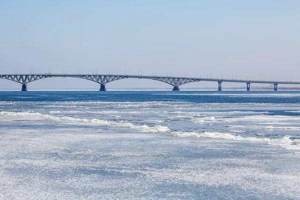 El hielo de primavera deriva en el río Volga. Puente de carretera en la ciudad de Saratov. Rusia. Un día soleado en marzo. Cielo azul — Foto de Stock