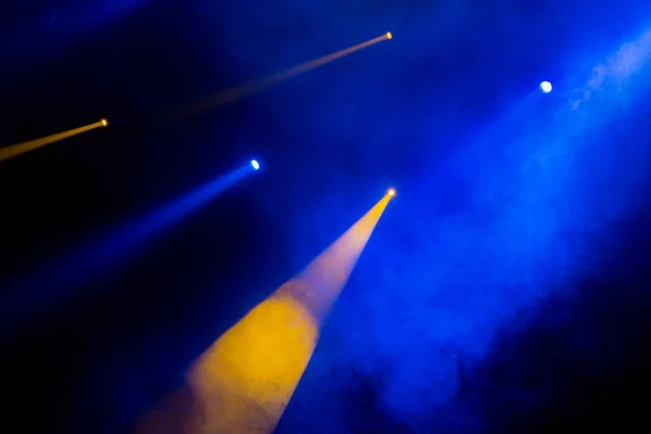 A luz azul-amarela dos holofotes através da fumaça no teatro durante a apresentação. Equipamento de iluminação . — Fotografia de Stock