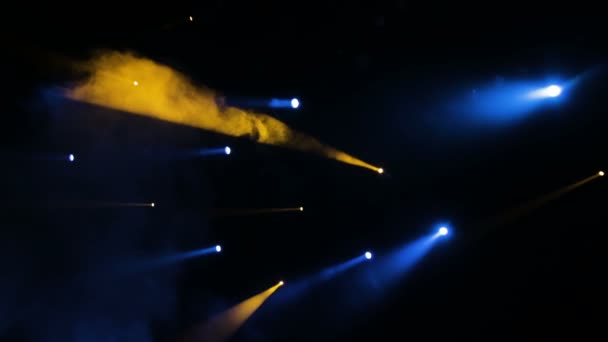 The blue-yellow light from the spotlights through the smoke in the theatre during the performance. Lighting equipment. — Stock Video